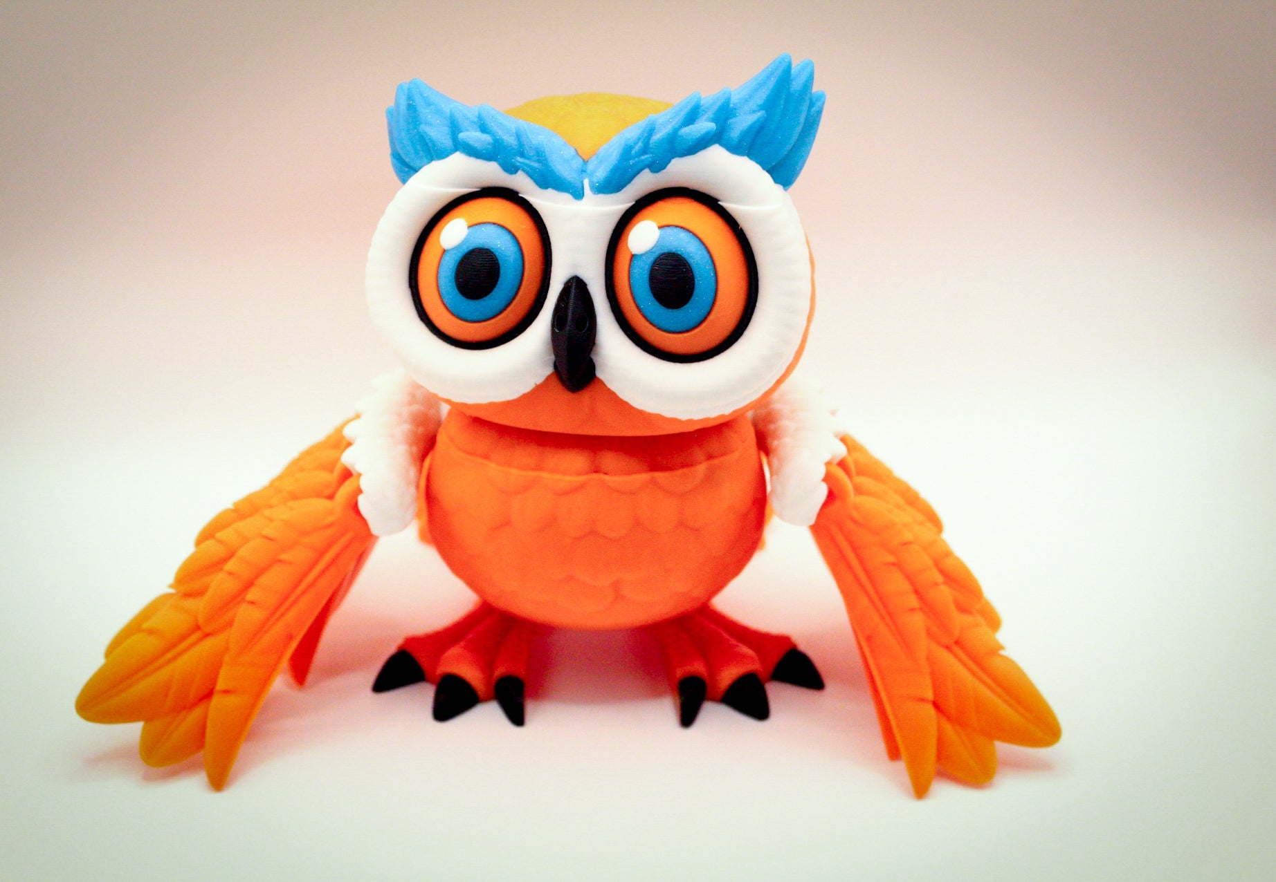 Articulated 3D printed owl toy with colorful features and articulated wings.